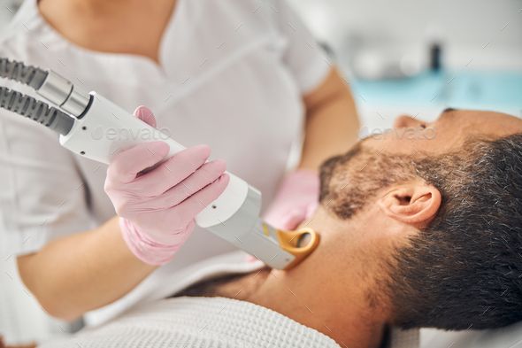 Unshaven young man having laser hair removal procedure